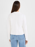 The model wears a fitted white knit sweater featuring a stand collar and a prominent vertical center back seam.