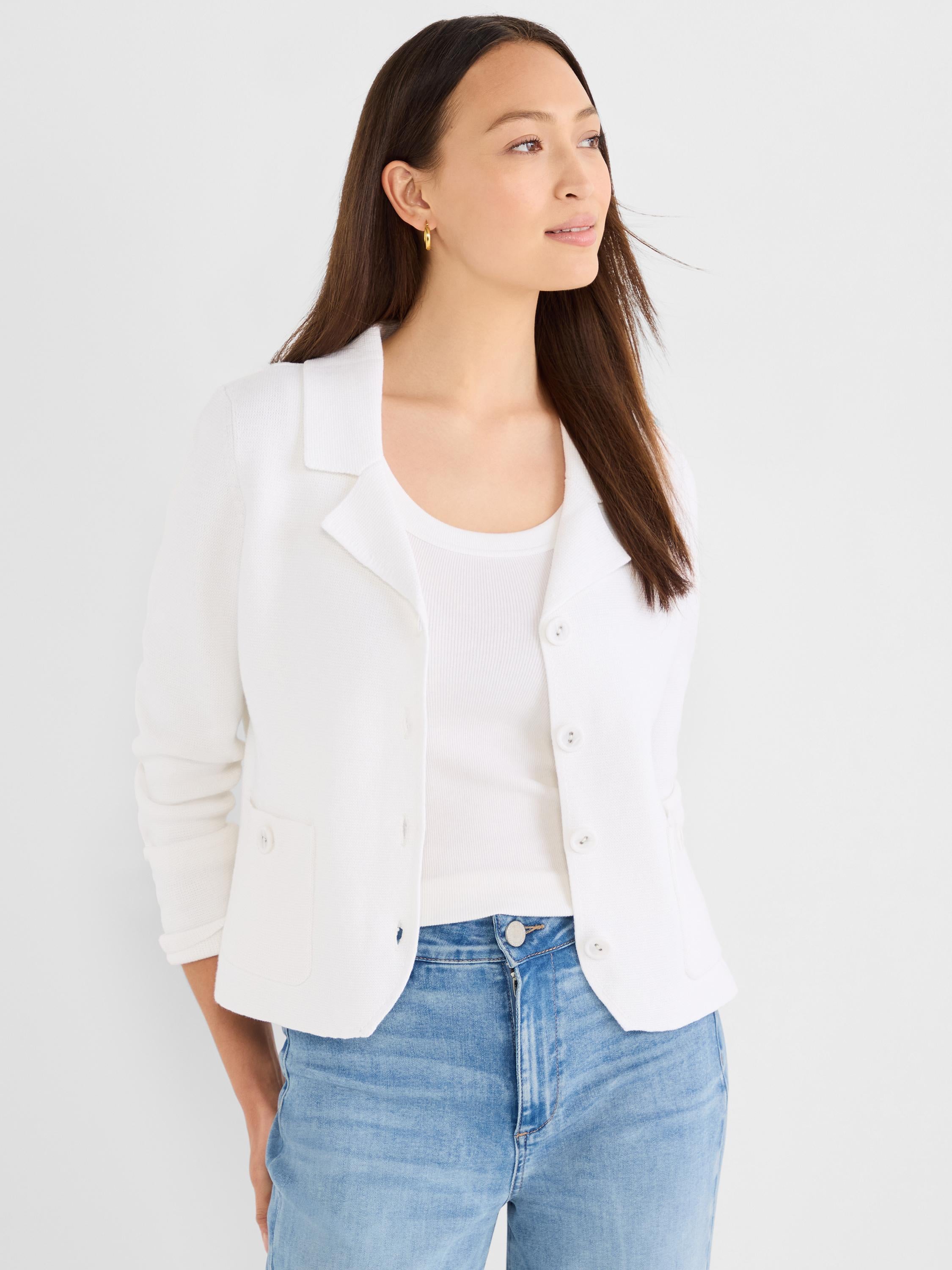 A model wears a white structured knit jacket featuring a lapel collar, button front closure, and patch pockets.