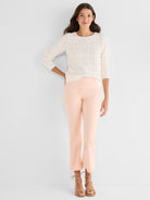 A model wears a white and peach wavy textured sweater with peach slim fit cropped flare pants and tan strappy sandals.