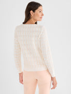 This white fitted sweater features a peach wavy knit pattern and long sleeves for a soft textured look.