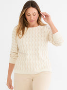 A cream relaxed-fit sweater featuring an allover open-knit wavy pattern and ribbed cuffs.