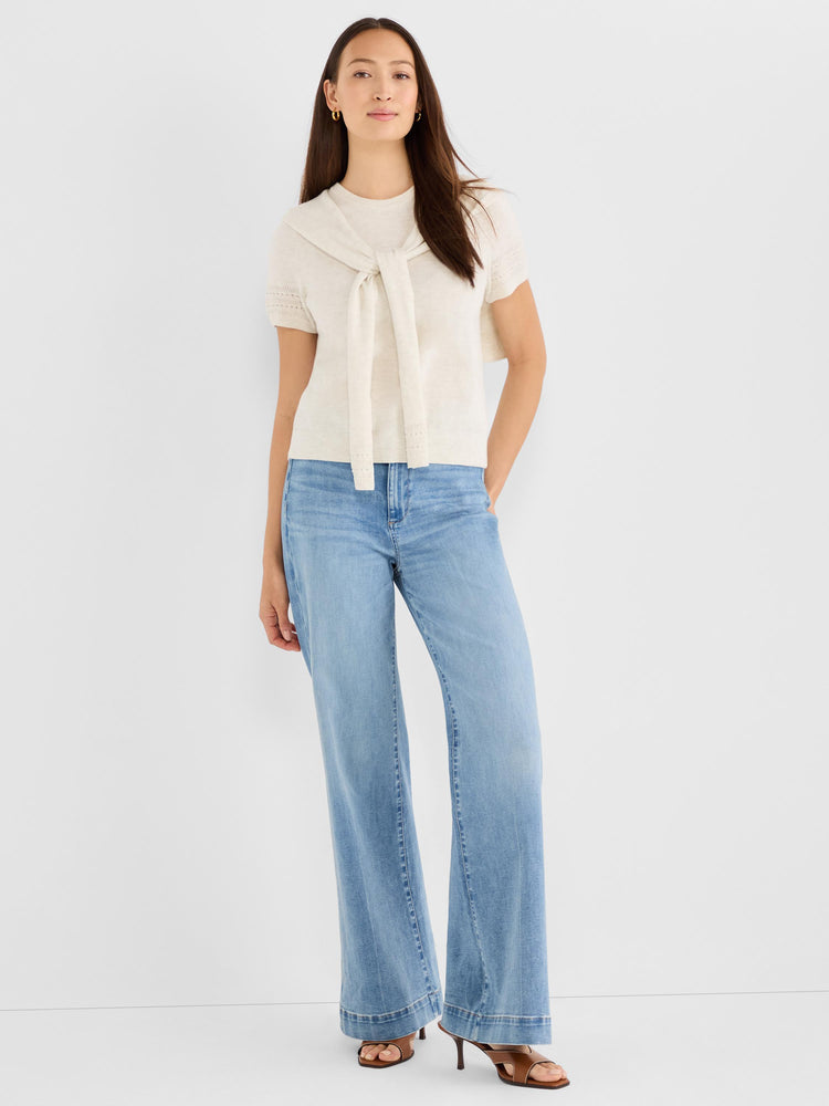 Cream short-sleeve knit top styled with a neck tie, worn with high-rise wide-leg light wash jeans.