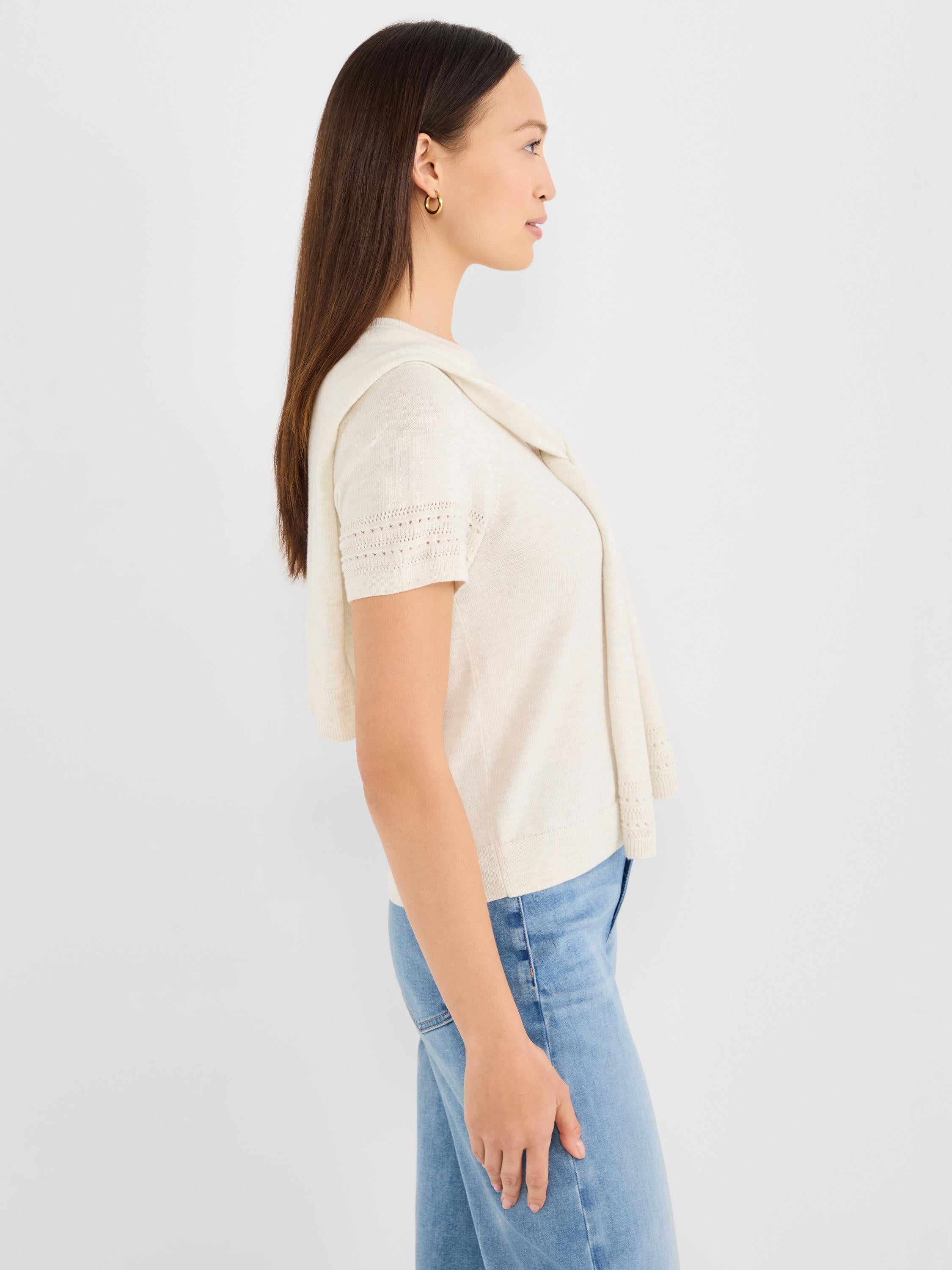 Ivory short-sleeve knit top featuring pointelle sleeves and a matching knit layer draped over the shoulders.
