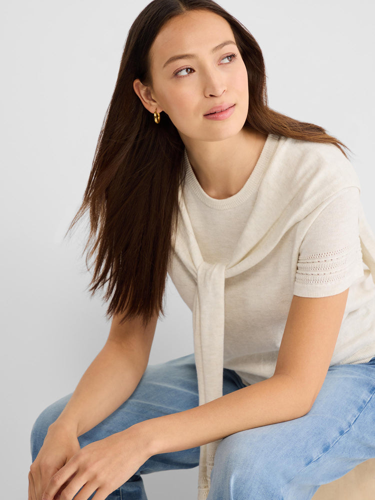Cream short-sleeve knit top with eyelet cuff detail, styled with a matching sweater tied draped over the neck.