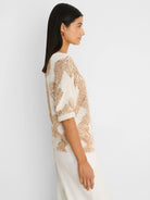 Cream and tan knit sweater with an irregular, abstract pattern and short cuffed sleeves.
