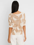 Back view of a cream and tan knit sweater with a cobblestone pattern and elbow-length sleeves on a model.