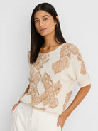 Off-white knit sweater with light brown cobblestone stamp pattern, boat neck, short sleeves, and rolled cuffs.