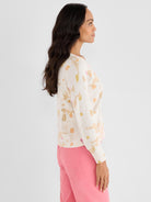 A standard-fit cream sweater with long sleeves showcases an abstract pastel print in warm tones.