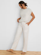 Light beige shimmering sleeveless cocoon sweater, round neck.