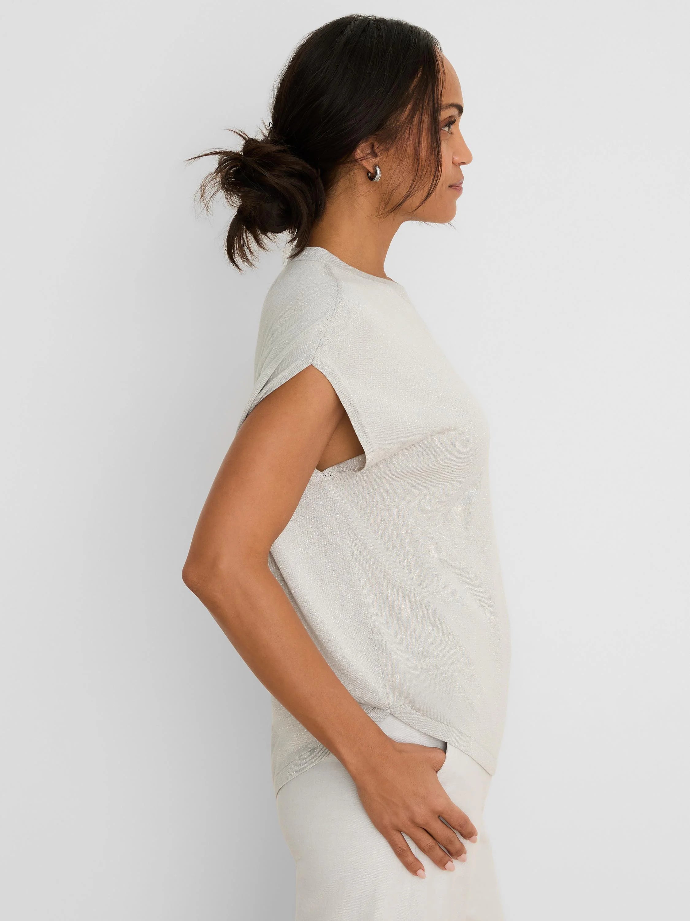 Shimmering pale gray-beige cocoon sweater with split short sleeves, worn by a model in profile.