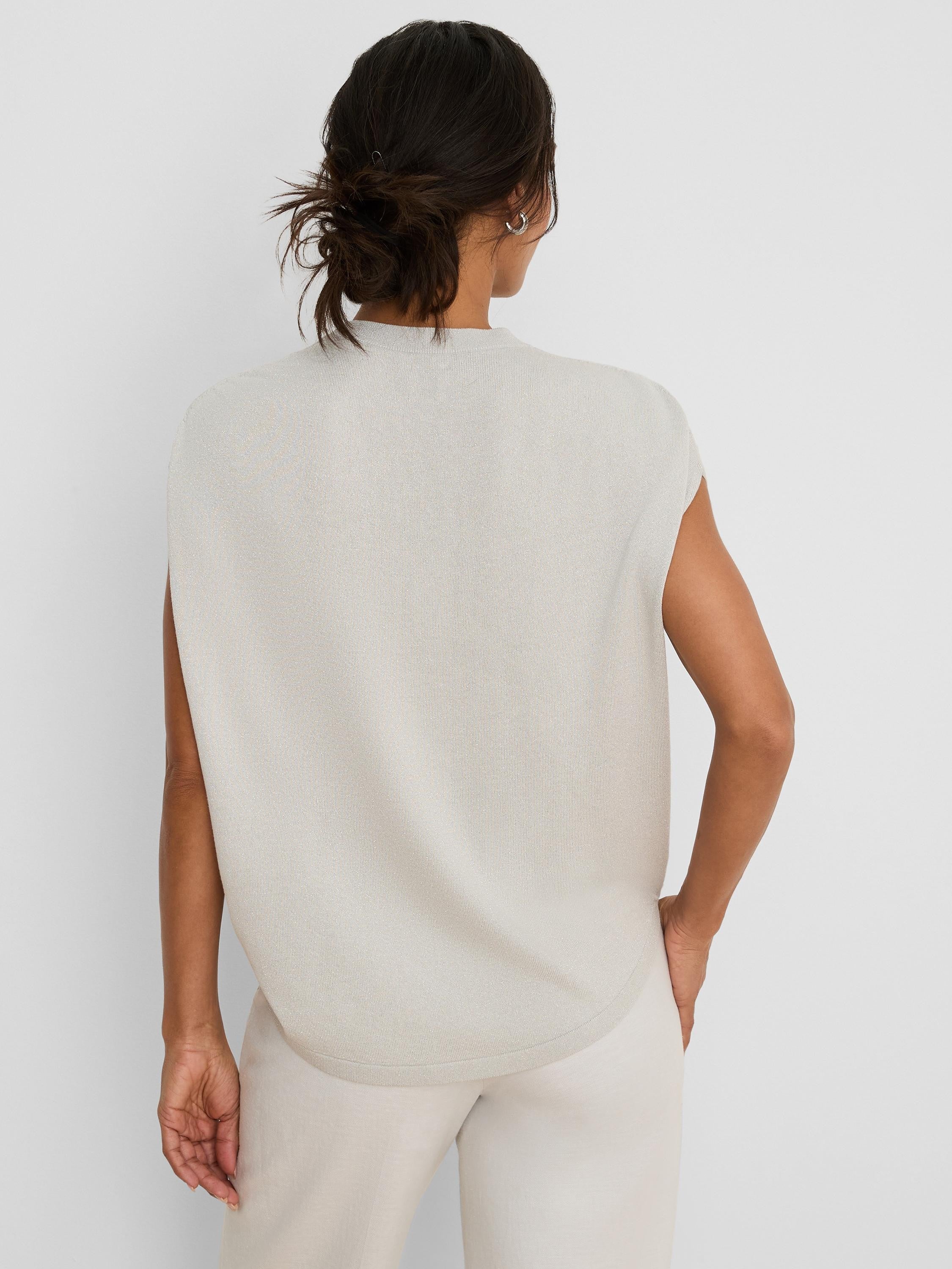 Back of a pale beige, sleeveless knit sweater with a mock neck. Features a relaxed fit and rounded hem.