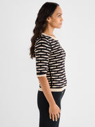 A fitted black and beige textured knit top with horizontal stripes, featuring elbow-length sleeves and a subtle boat neckline.