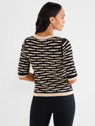 The model wears a fitted black and beige half-sleeve knit top with textured horizontal stripes and contrasting trim.