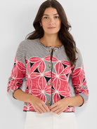 Cropped fitted cardigan with a mixed knit pattern of bold pink florals on the body and narrow black and white stripes on.