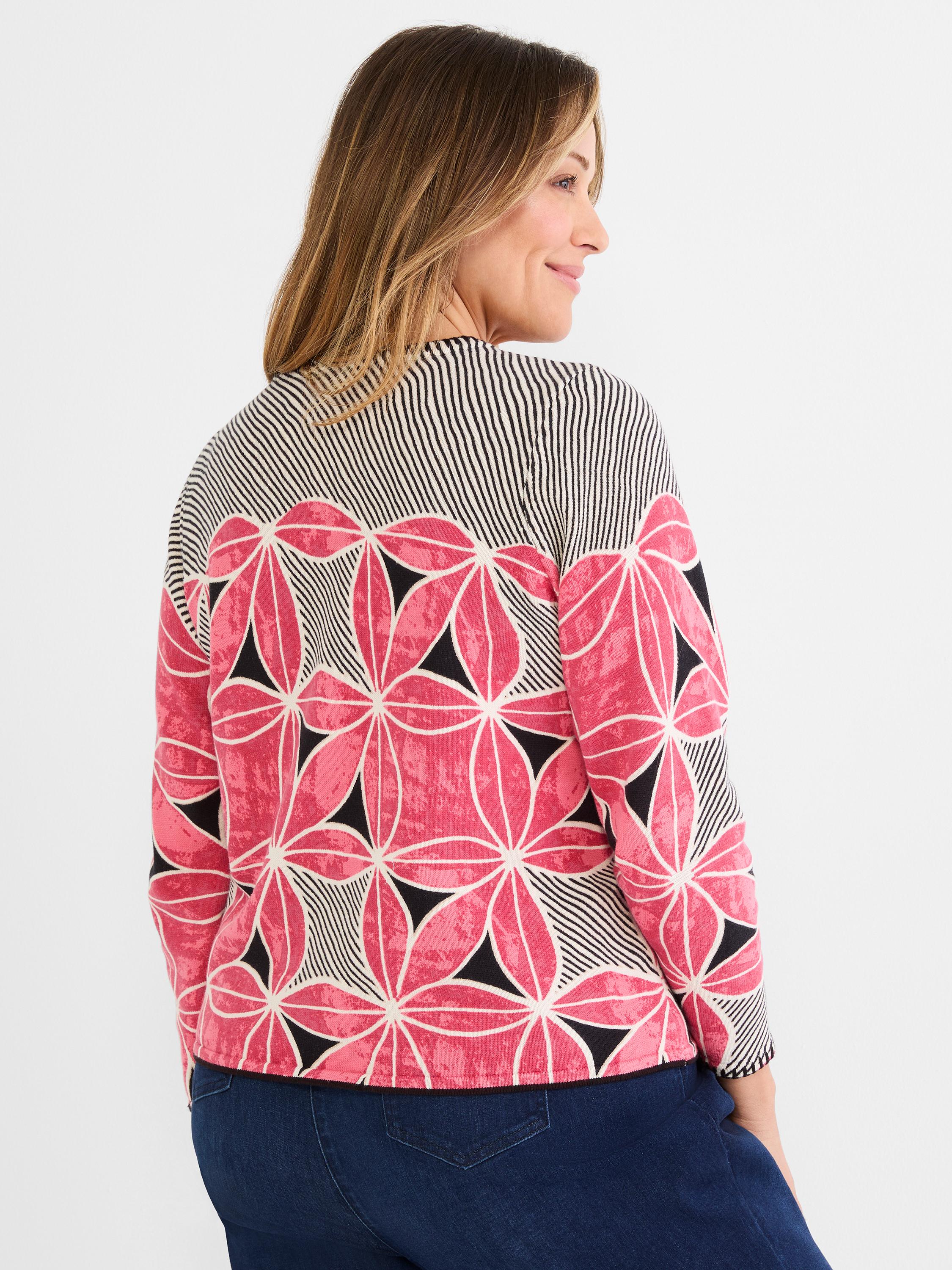 Knit sweater with a bold pink, black, and white geometric floral pattern on the body and striped shoulders.