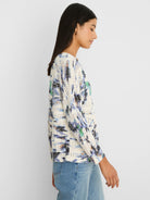 Cream pointelle knit sweater with an abstract pattern of blue, black, green, and peach-orange patches.