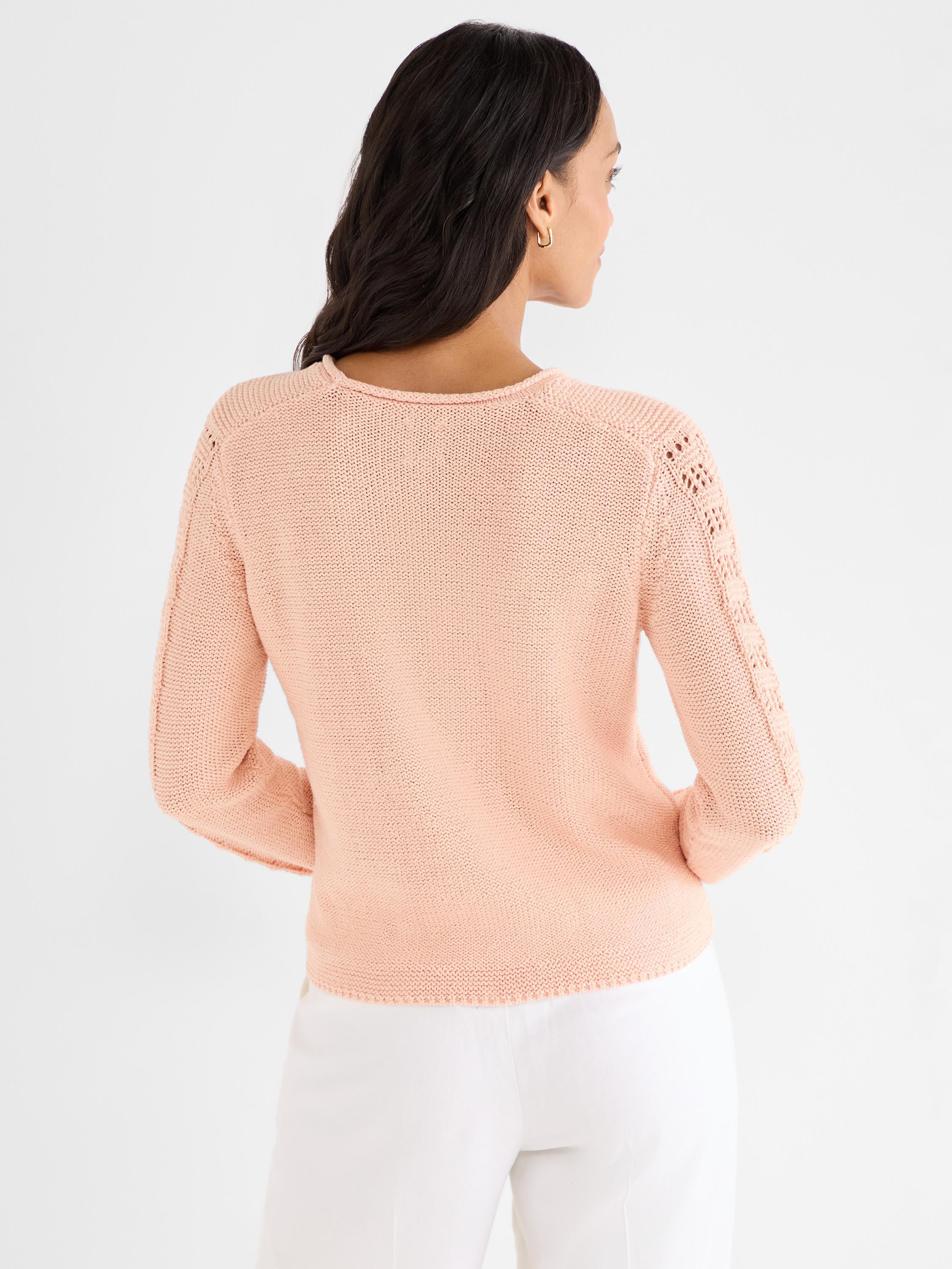 Model wears a blush knit sweater featuring a standard fit, round neck, and long sleeves detailed with vertical open-knit.