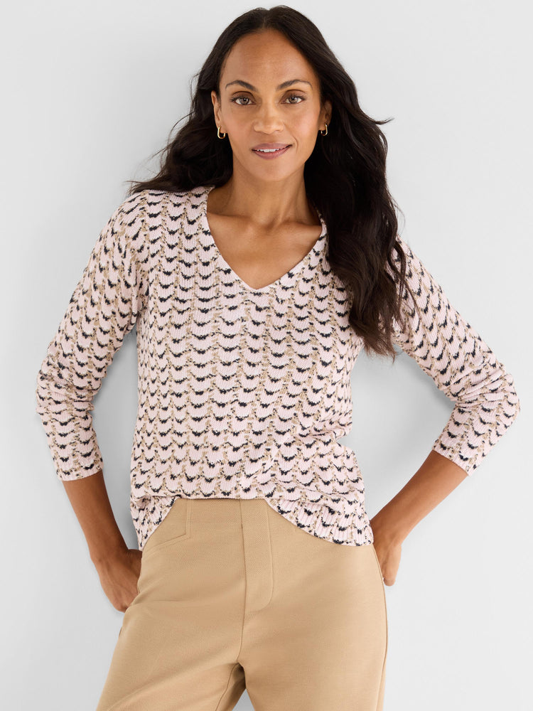 A pink and black chevron pattern knit top has a V-neckline and fitted three-quarter sleeves.