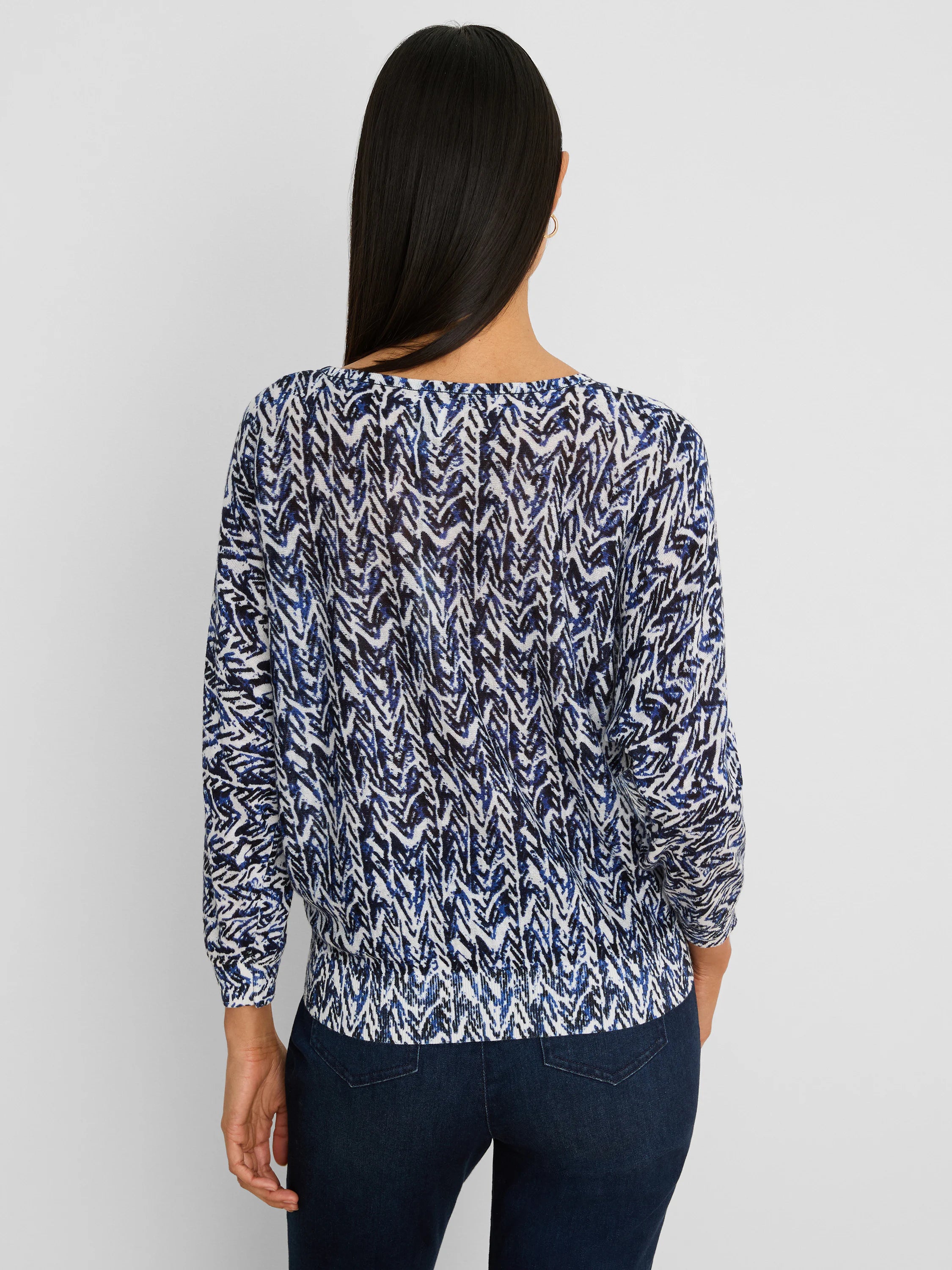 Indigo Crosshatch Sweater on a model, back view. Pattern in indigo, blue, black, and white. Has long sleeves & ribbed hem.