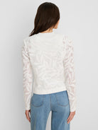 White jacket with an open-knit leaf pattern, shown from the back on a model wearing blue jeans.