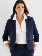 A textured navy knit jacket with a single button and flap pockets is styled casually over a crisp white shirt.