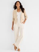 A cropped beige textured knit jacket with a single button closure is paired with flowy, high-waisted cream trousers.
