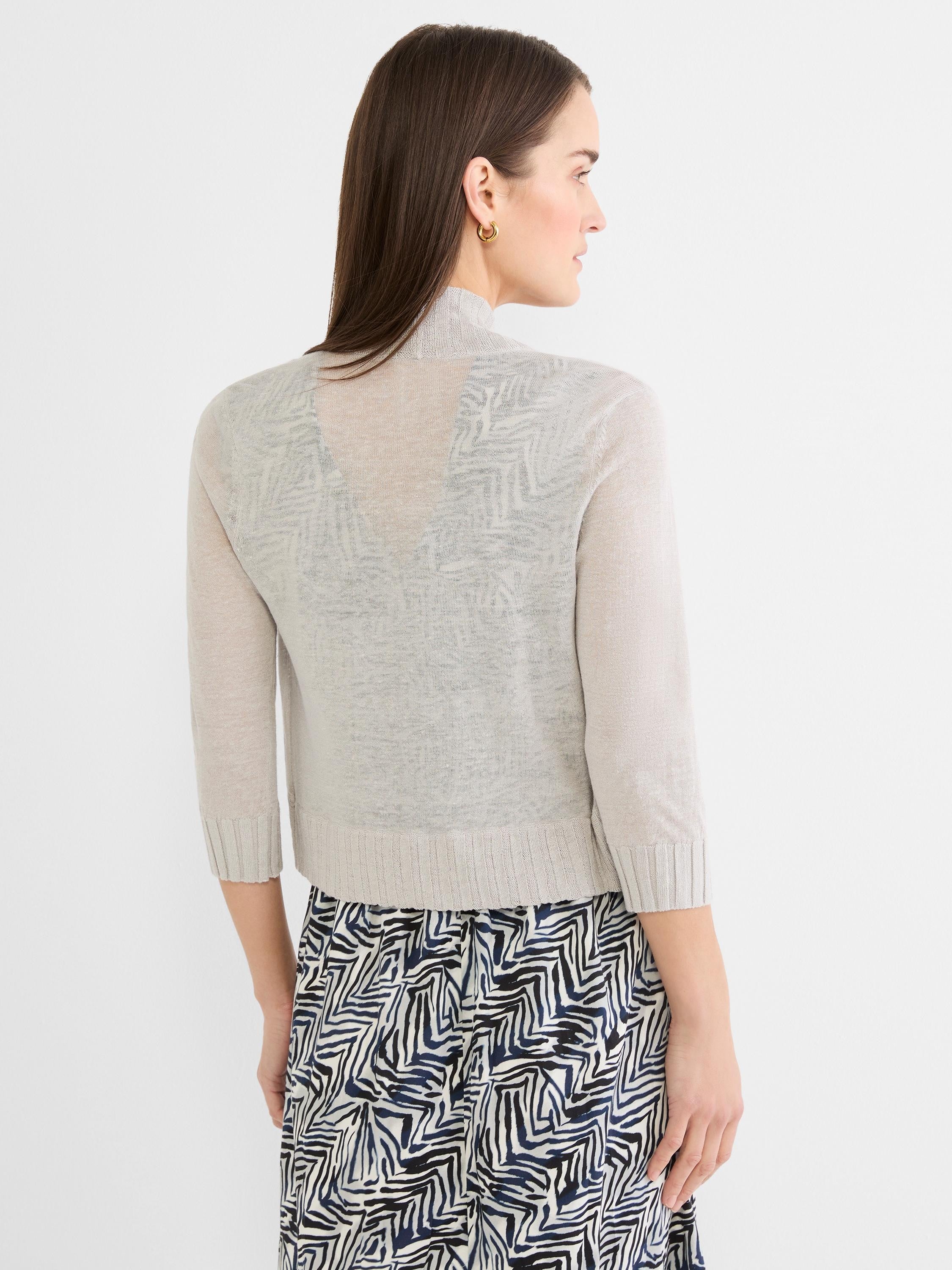 Light grey bolero cardigan with sheer knit, subtle back pattern, 3/4 ribbed sleeves, and mock neck. Waist-length.