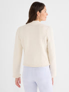 Fitted cream textured jacket featuring a mock neck collar and fringed detailing at the hem and cuffs.