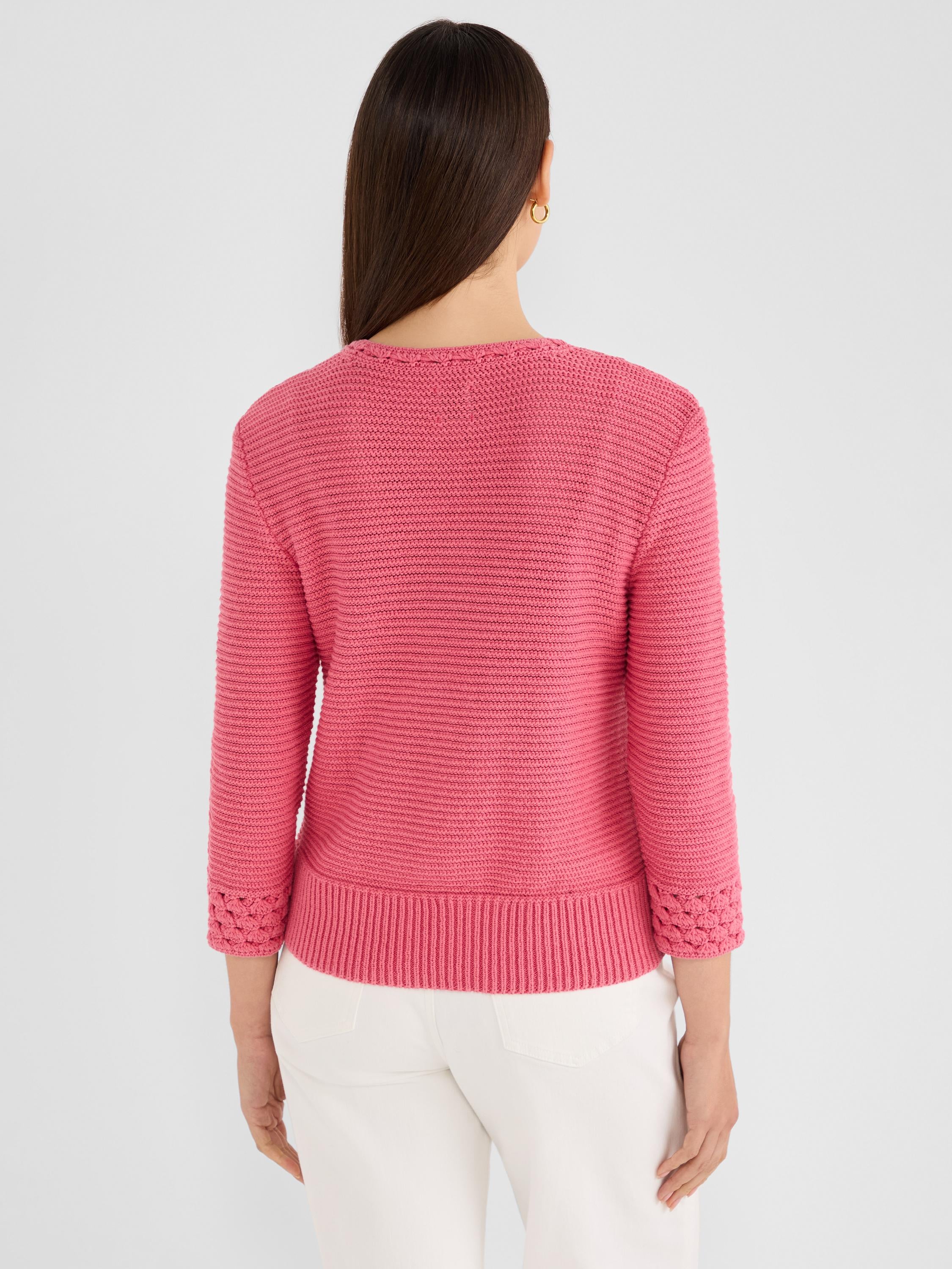 Pink textured sweater with three-quarter sleeves and a structured rib knit, finished with decorative crochet cuffs.