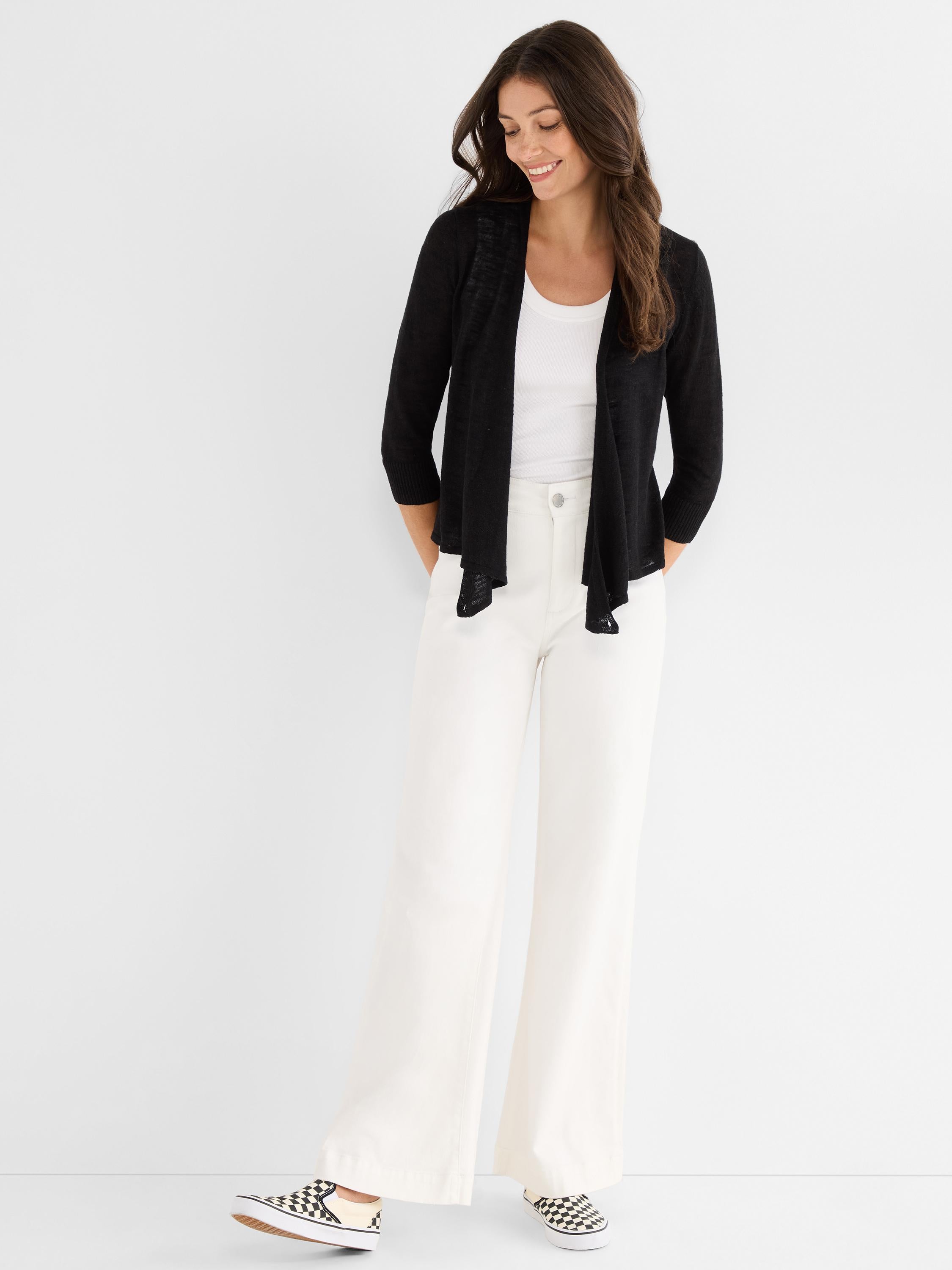 A sheer black knit open cardigan is worn, featuring a draped front and three-quarter length sleeves.