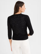 This lightweight black sheer sweater has a fitted shape, three-quarter raglan sleeves, and a ribbed hem.