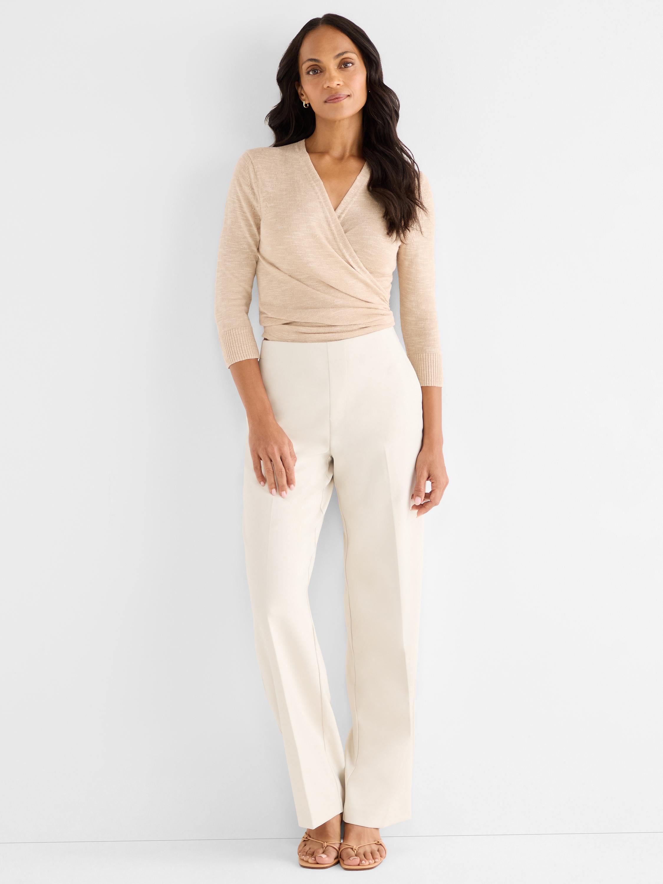 A fitted tan knit wrap sweater is paired with tailored cream wide-leg pants.