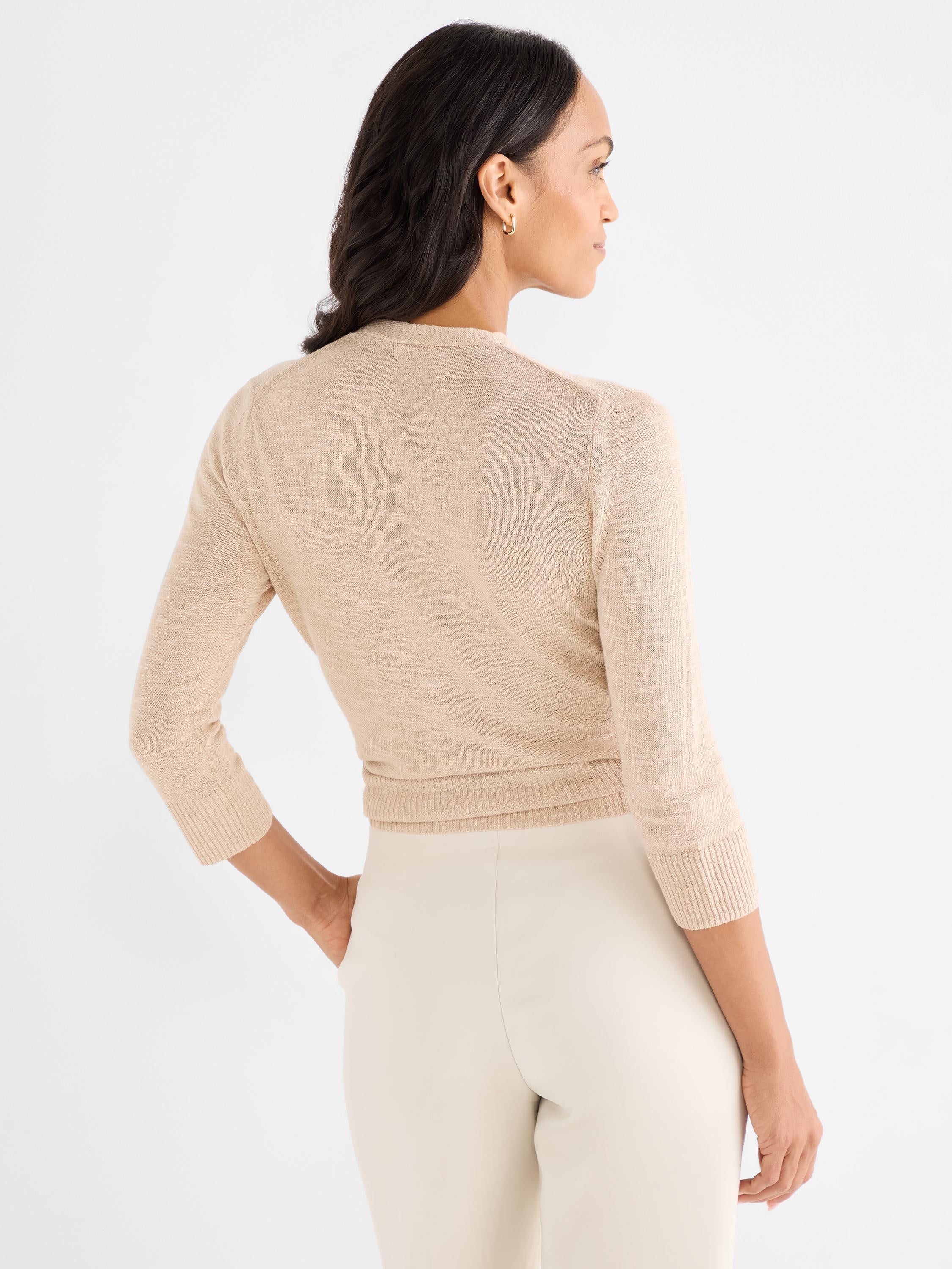A fitted, light beige cropped cardigan features sheer fine knit fabric and three-quarter sleeves.