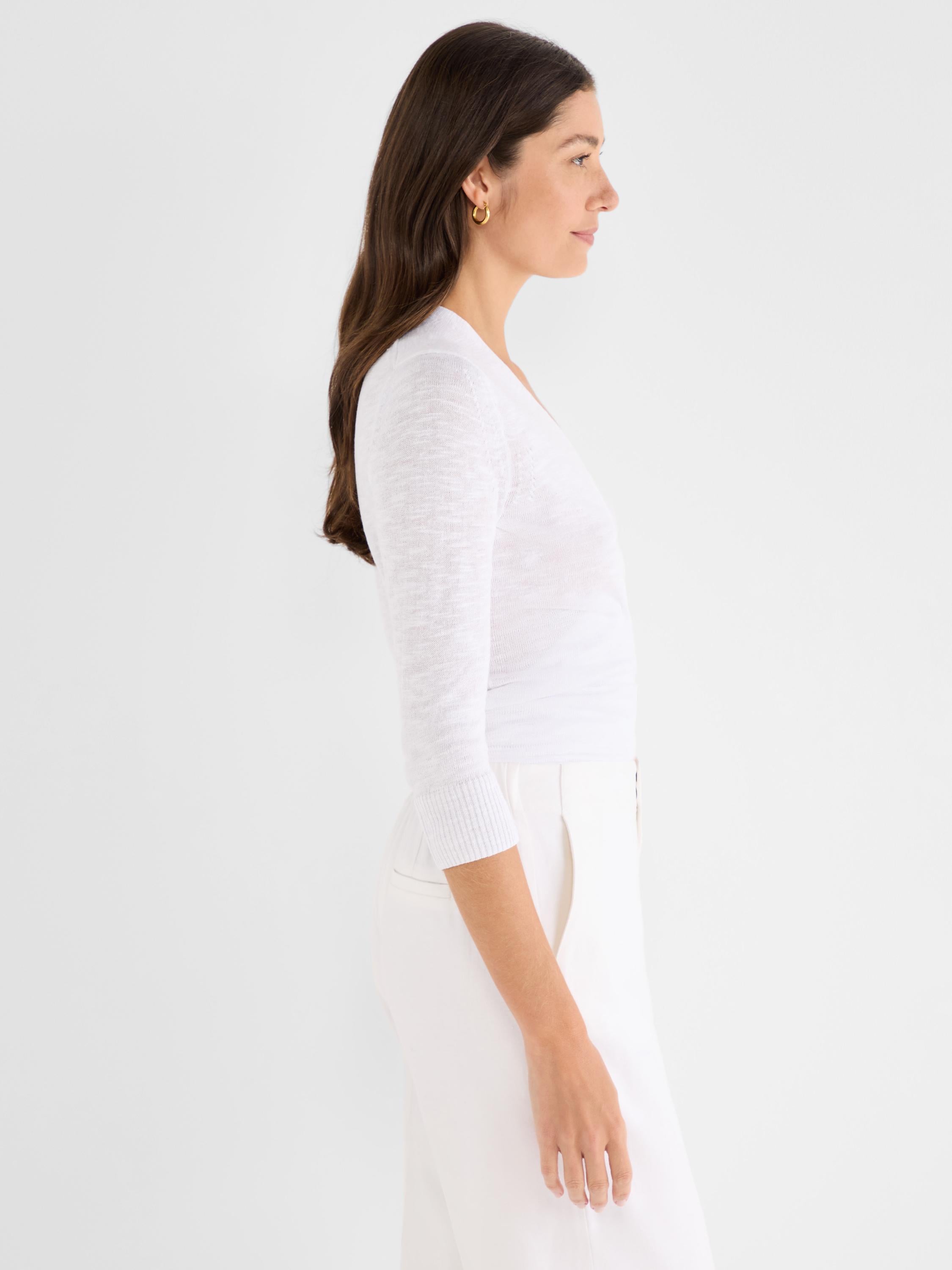 White lightweight knit top has a slim fit, V-neck, and three-quarter sleeves with ribbed cuffs.
