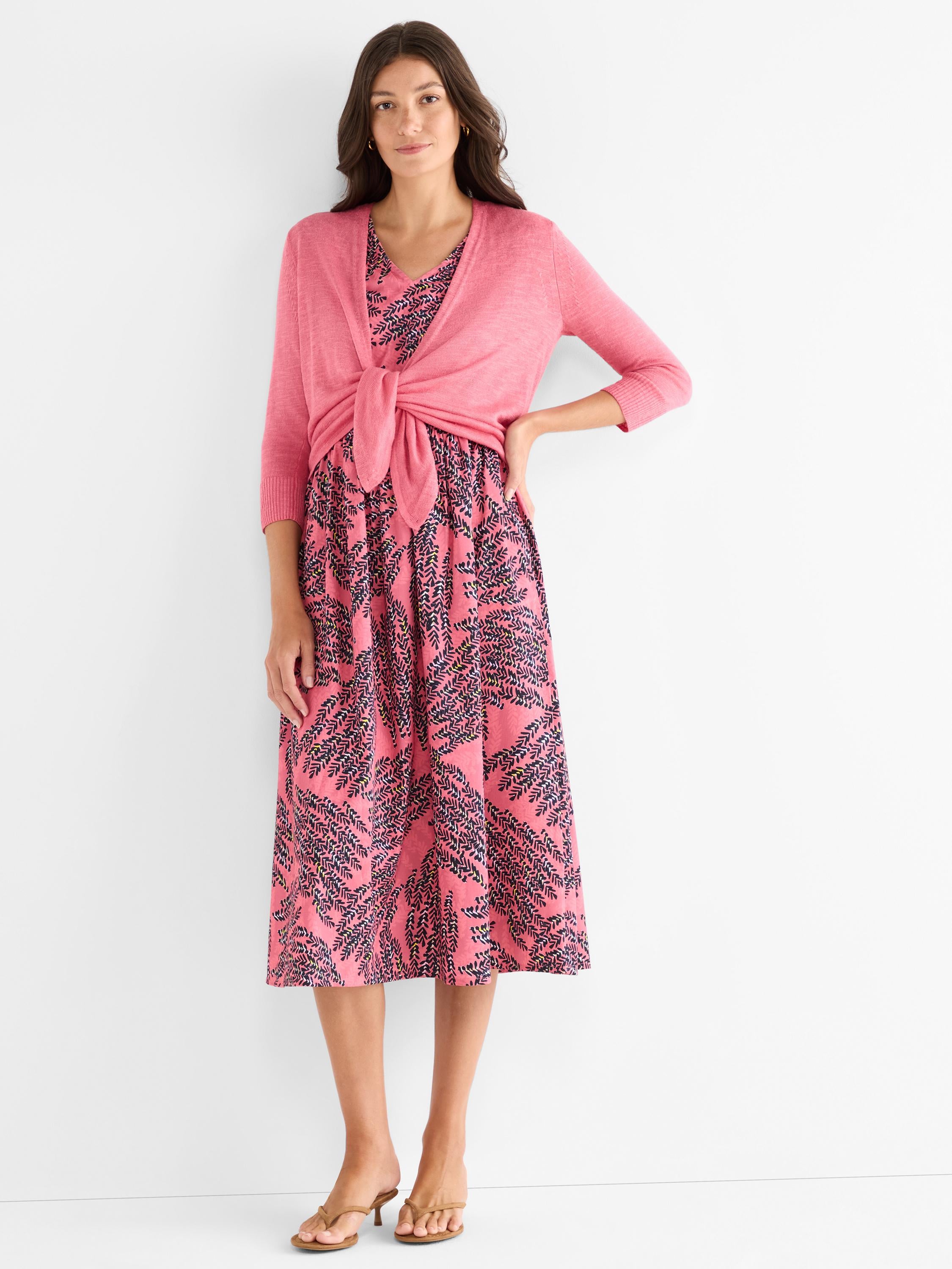 She wears a rosy leaf print midi dress and a matching pink tie-front cardigan with three-quarter sleeves.