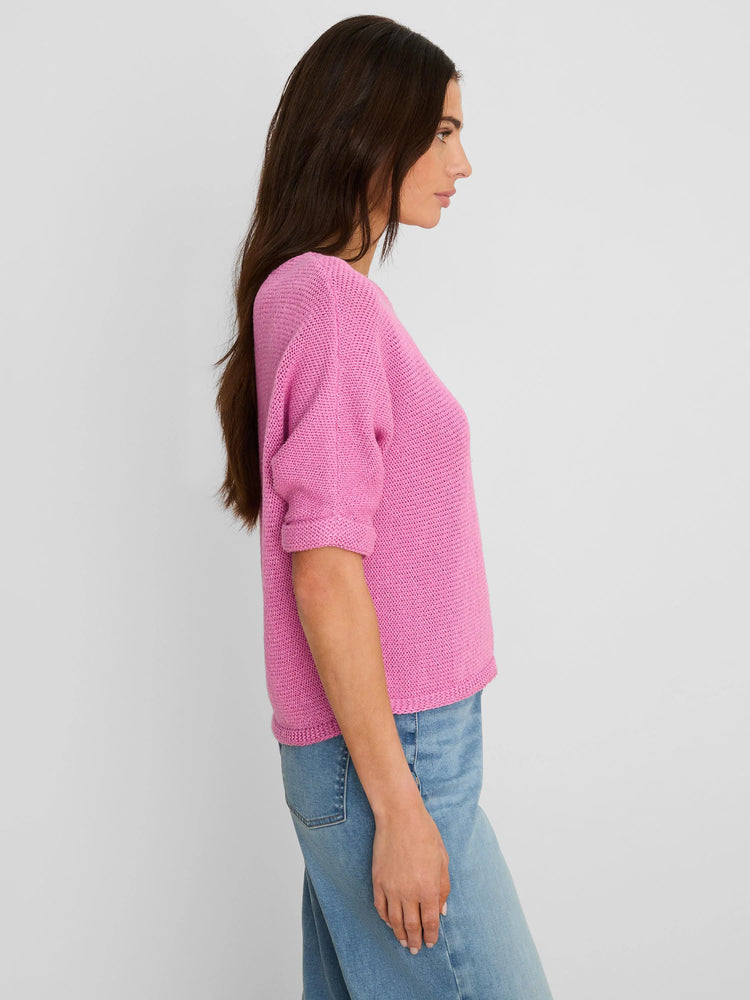 Bright pink crimpy cord knit sweater with rolled sleeves, shown on a model.
