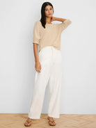 Light beige textured knit sweater with elbow-length rolled sleeves and a wide neckline.