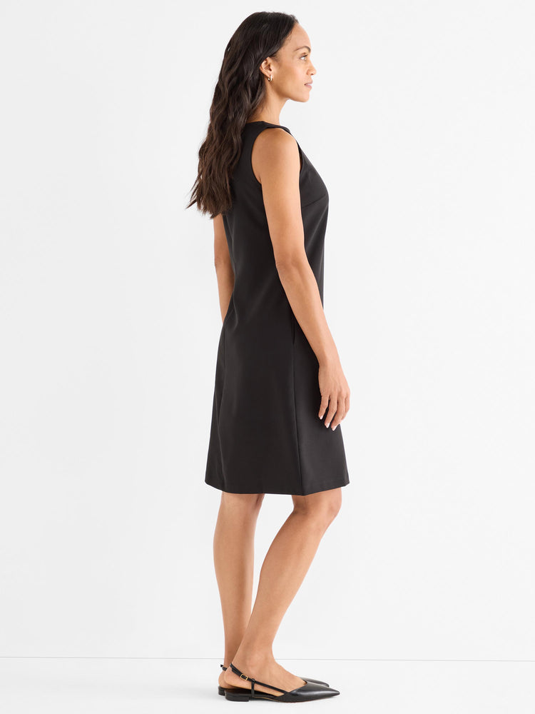 A model wears a classic, tailored black sleeveless sheath dress featuring a clean design and hitting above the knee.