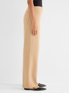 Tan high-waisted pants with a wide straight leg feature structural stitched seams and front slash pockets.