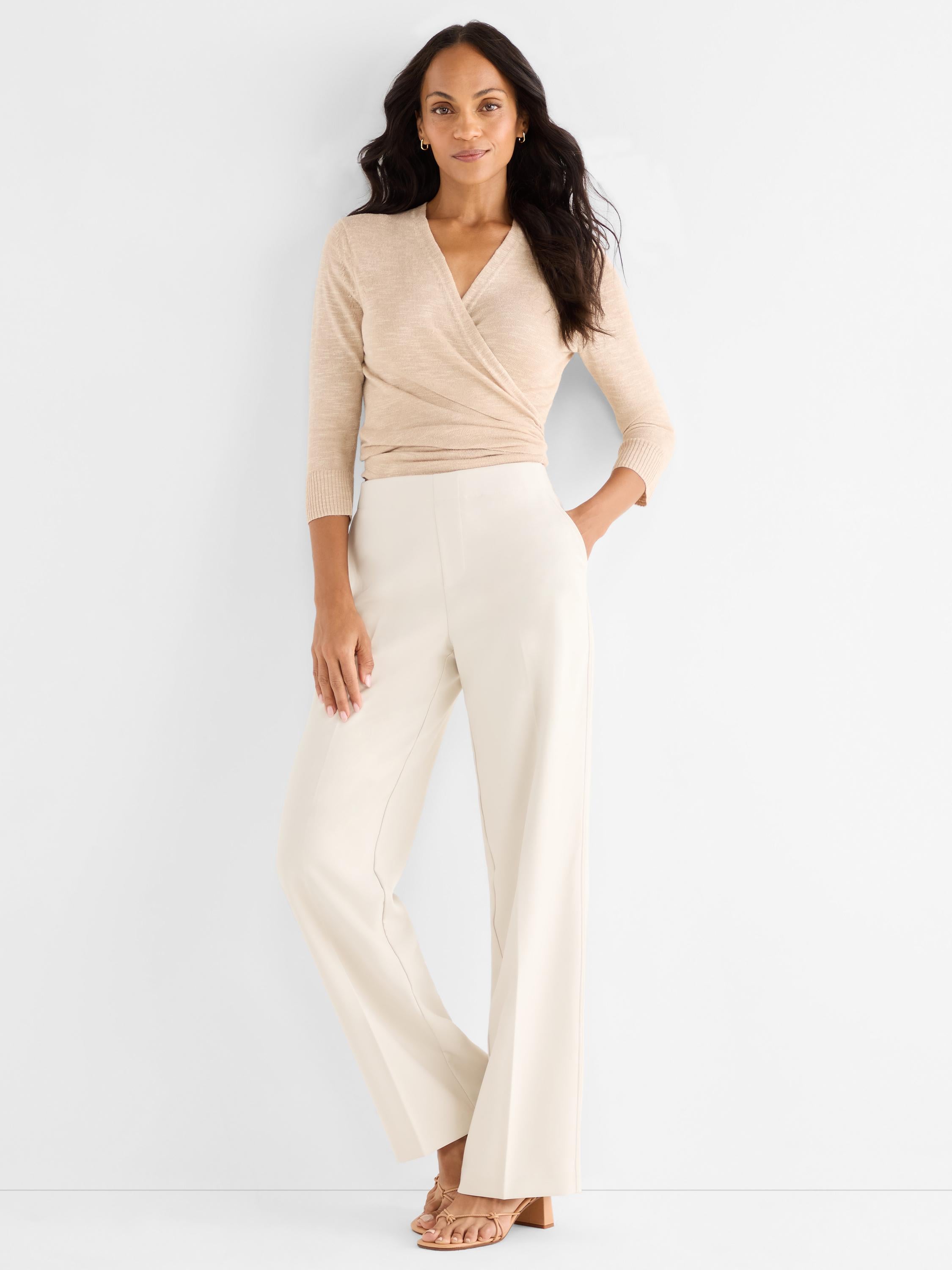 A model wears a fitted beige knit wrap top with high-waisted cream wide-leg trousers.