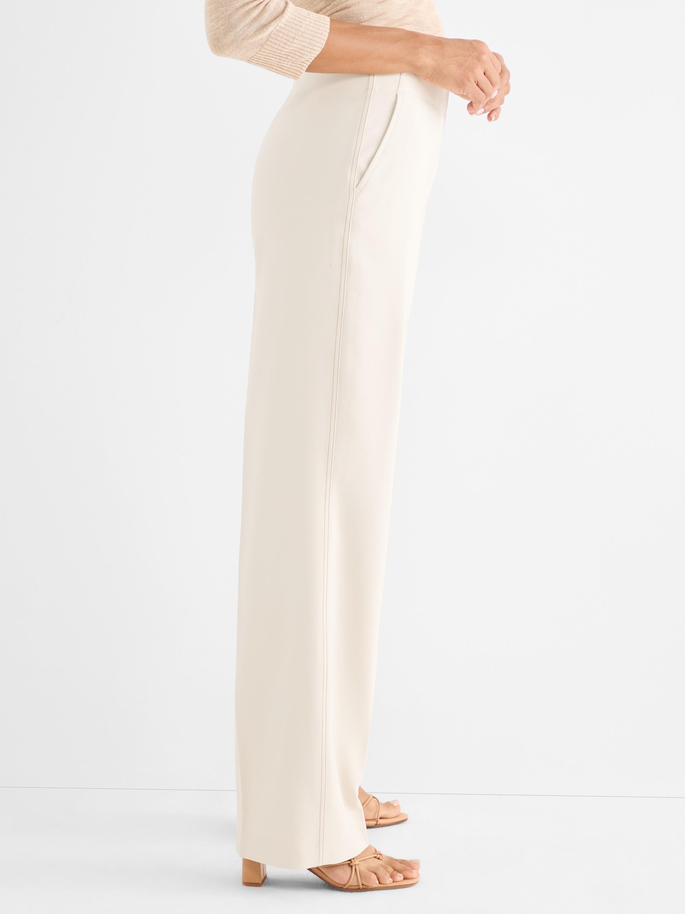 Cream wide-leg trousers with a high waist and stitched front seam detail are worn by the model.