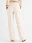 Elegant cream wide-leg trousers are styled high-waisted, showcasing a long, fluid drape and sharp pressed creases.