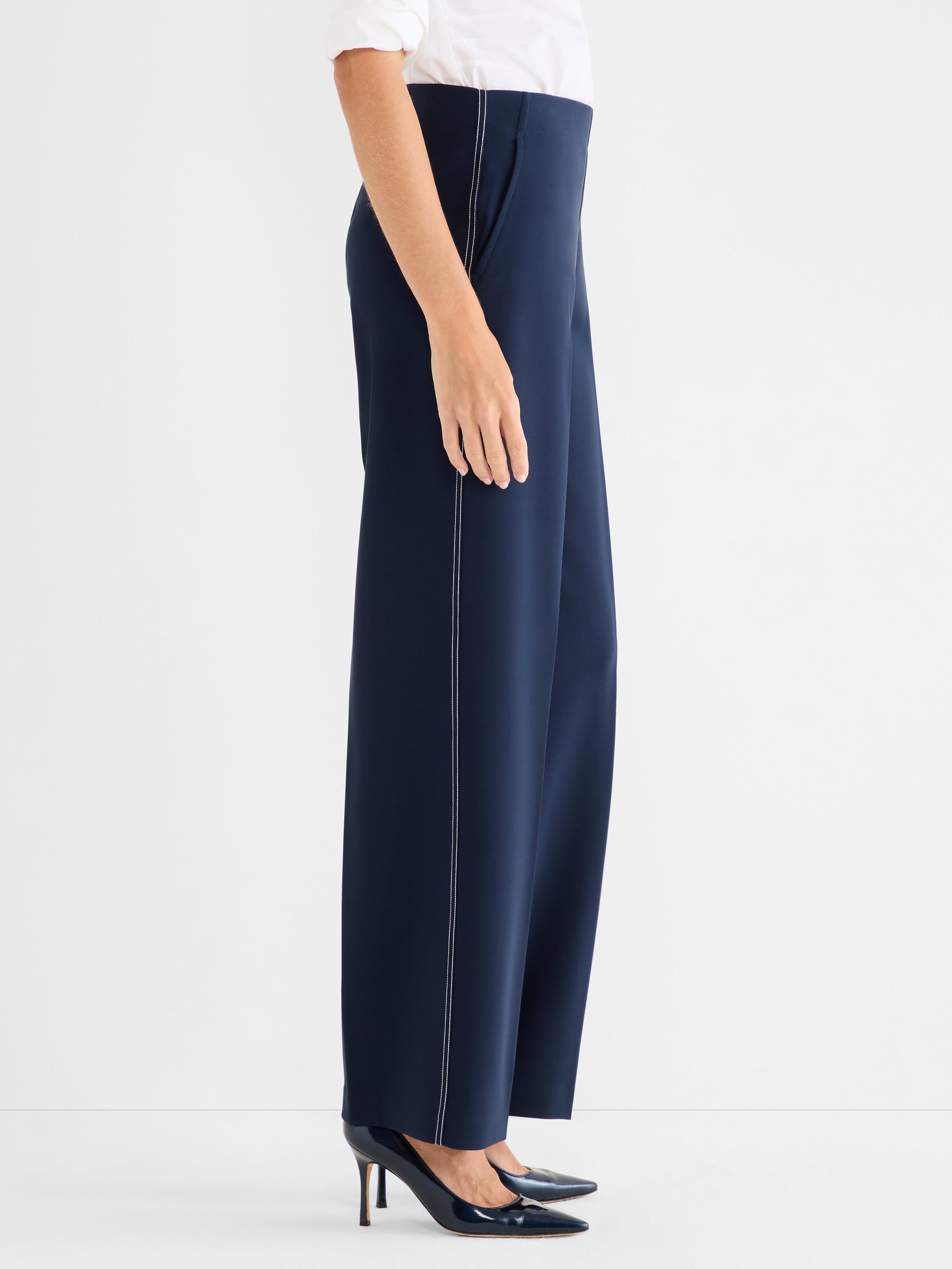 Navy high-waisted wide-leg trousers with white contrast stitching detailing the outer seams.