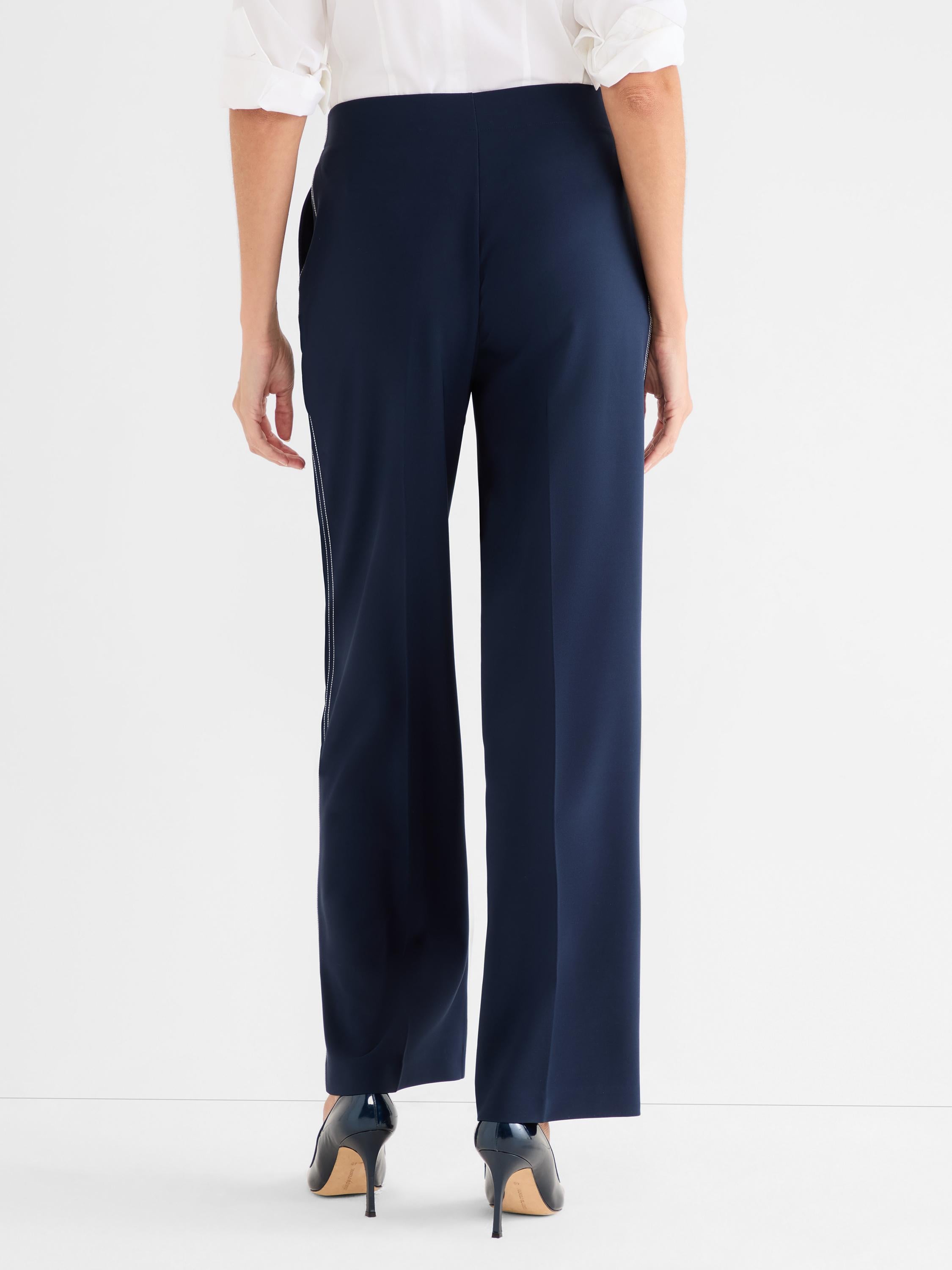 Navy high-waisted wide-leg trousers feature subtle vertical contrast white piping detail along the outer seams.