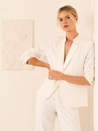 Ecru blazer, open front lapel, sleeves pushed up revealing two tan cuff buttons.