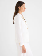 Off-white blazer with an open front, gold buttons, and flap pockets, modeled in profile.