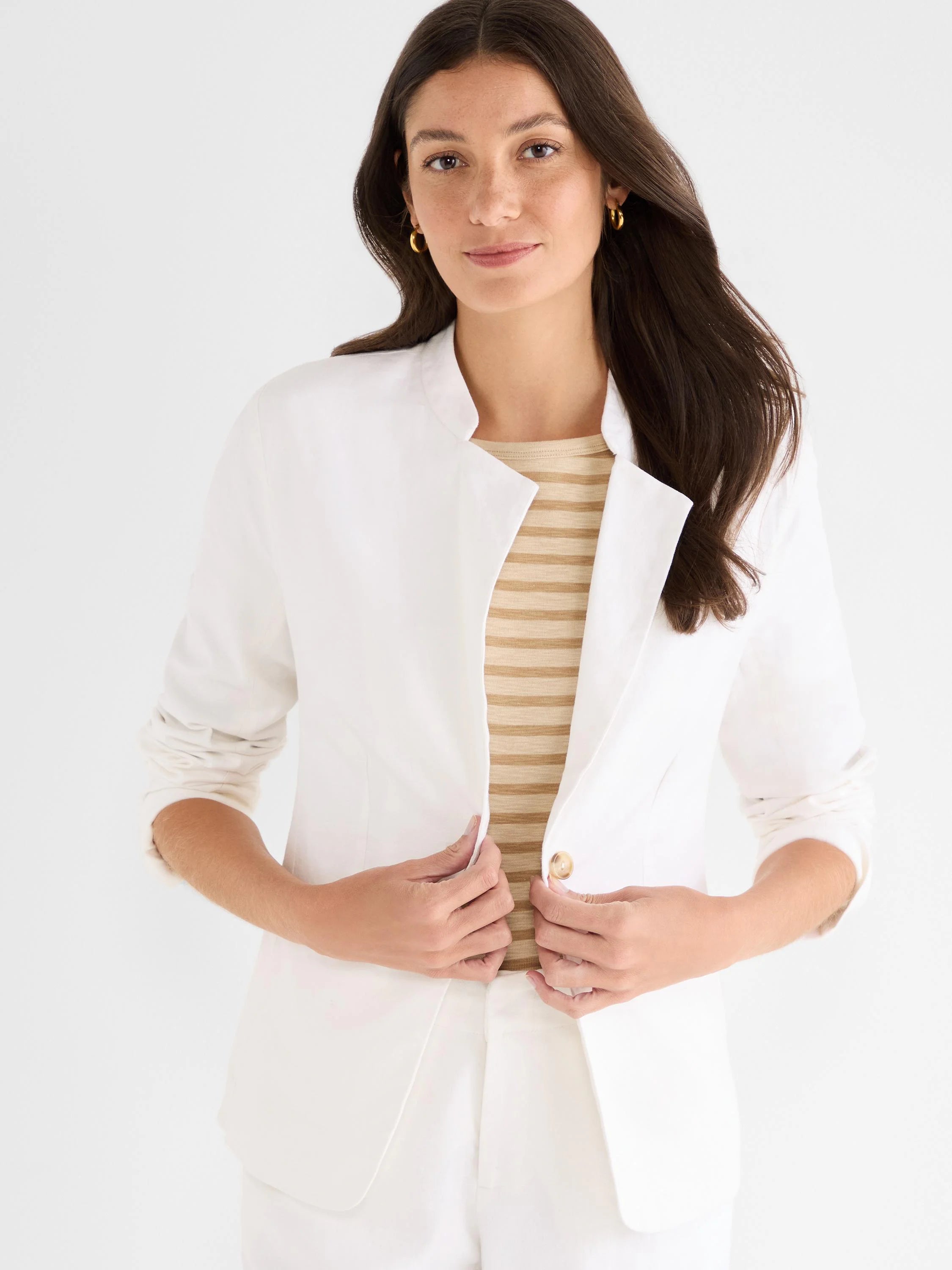 White linen blazer with a stand collar, single tan button closure, and sleeves rolled to the elbows.