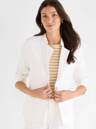 White linen blazer with a stand collar, single tan button closure, and sleeves rolled to the elbows.