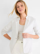 Light beige stretch linen blazer, worn open, with soft lapels and sleeves pushed up.