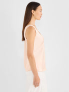 Light peach sleeveless tank with a smooth, glossy woven texture and a V-neck.